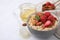 Delicious oatmeal with freeze dried strawberries, almonds and mint on white tiled table, closeup. Space for text