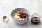 Delicious oatmeal porridge with butter and jam in a gray bowl on a light gray background