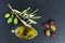 Delicious olive oil, black and green olives with leaves, over black stone slate background