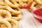 Delicious onion rings with ketchup on a wooden cutting board