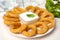Delicious onion rings with sauce on white table, closeup
