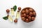 Delicious organic Macadamia nuts, green leaves and natural oil on white background, flat lay