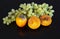 Delicious Oriental fruits persimmon and a bunch of grapes on a dark glass surface