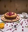 Delicious pancakes with berries and a cup of tea, honey and spoon wooden rustic background close up
