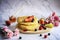 Delicious pancakes with fresh berries and honey on marble patterned floor. Foreground pink carnation and background with honey and