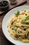 Delicious pasta with anchovies, olives and basil on wooden table, closeup