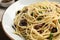 Delicious pasta with anchovies, olives and parmesan cheese on wooden table, closeup