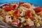 Delicious pasta salad or Mediterranean salad. Tomatoes with mozzarella basil corn spice and olive oil on a wooden table.