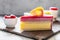 A delicious piece of mango and berry mousse cake. Juicy mouth-watering dessert next to a bowl of raspberries