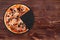 Delicious pizza with ham, mozzarella, mushrooms and olives, without a quarter on a black slate platter which is on wooden table