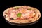 A delicious pizza with tomato sauce, mozzarella, prosciutto and fresh basil with reflection
