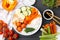 Delicious poke bowl and ingredients on black wooden table, flat lay