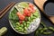 Delicious poke bowl with lime, fish and edamame beans on black table, flat lay