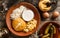 Delicious polenta with cheese, scrabble egg and sour cream on plate on rustic wooden background. Traditional Romanian food, top