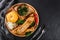 Delicious polenta with Grilled fillet fish, cheese and spice sauce on cutting board over black stone background. Hot fish Dishes.