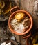 Delicious polenta with meat, cheese and sour cream in bowl on rustic wooden background. Traditional Romanian food, top view