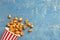 Delicious popcorn with caramel in paper bucket on wooden background, top view