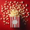 Delicious popcorn scattering from a red striped carton box on red background with copy space