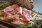 Delicious pork bacon sliced â€‹â€‹into strips on a wooden background with spices and fresh thyme. A serving of low-fat succulent