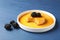 Delicious pudding with caramel and blackberries on blue wooden table