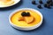 Delicious pudding with caramel and blackberries on blue wooden table