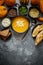 Delicious pumpkin soup with cream, seeds, bread and fresh herbs in elegant ceramic black bowl