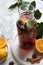 Delicious punch drink in bottle, spices and citrus fruits on white marble table