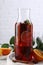 Delicious punch drink in bottle, spices and citrus fruits on white table