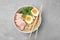 Delicious ramen with meat on light grey table, top view. Noodle soup