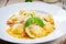 Delicious Ravioli dish served in a white plate with steam rising above, garnished with fresh basil leaves