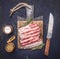 Delicious raw bacon, rosemary, knife and spices on a cutting board wooden rustic background top view close up