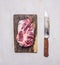 Delicious raw pork steak on a cutting board with a knife for meat wooden rustic background top view close up