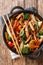 Delicious recipe for stir fried pork with broccoli, bok choy, carrots, peppers, cauliflower close-up in a pan. Vertical top view