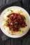 Delicious Reindeer meat served with potatoes and lingonberry sauce close-up in a plate. vertical top view