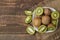 Delicious ripe many kiwi fruit and kiwi in a cut in a plate on a brown wooden table. top view. space for text