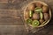 Delicious ripe many kiwi fruit and kiwi sectioned in a basket on a brown wooden table. top view. space for text