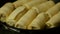 Delicious, rolled up, appetizing pancakes are fried in a row in frying pan with cooking oil. Cooking homemade food. Close-up.
