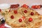 Delicious Russian pancakes with cherries and strawberries and a mug of milk on a bright table, top view, selective focus.