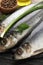 Delicious salted herrings and ingredients on black wooden table, closeup
