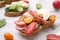 Delicious sandwich with burrata cheese, ham, radish and tomatoes on white marble table, closeup