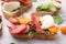 Delicious sandwich with burrata cheese, ham, radish and tomatoes on white table, closeup