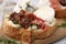Delicious sandwich with burrata cheese, ham and sun-dried tomatoes served on table, closeup