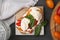 Delicious sandwich with burrata cheese and tomatoes served on grey wooden table, flat lay