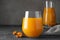 Delicious sea buckthorn juice and fresh berries on grey table, closeup