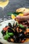 Delicious seafood mussels in sauce with glass of white wine Lemon and baguette. Clams in the shells. Fine dining in a seafood