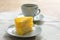 Delicious slice of orange cake served on white dish in coffee times on tablecloth