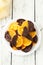 Delicious slices of orange coated chocolate on plate on the white wooden background