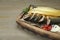 Delicious smoked mackerels with pepper, onion and spices on wooden table, closeup. Space for text