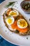 Delicious smoked salmon sourdough toast with goat cream cheese and cut boiled egg, garnished with dill, chives & pickled Capers