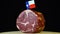Delicious smoked tenderloin with small flag of Texas, piece of meat rotating on balck background.